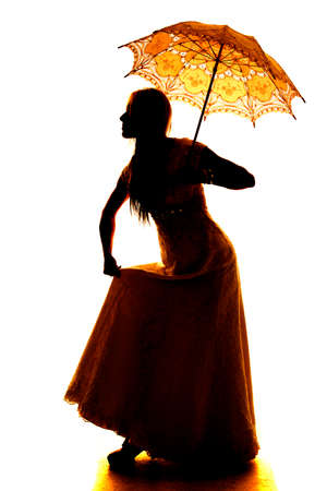 A silhouette of a woman in her dress, holding on to her umbrella.の写真素材