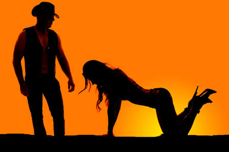 A silhouette of a woman on her knees with her cowboy looking down at her.の写真素材