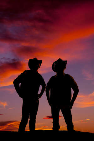 A silhouette of two cowboys standing in the outdoors.の写真素材