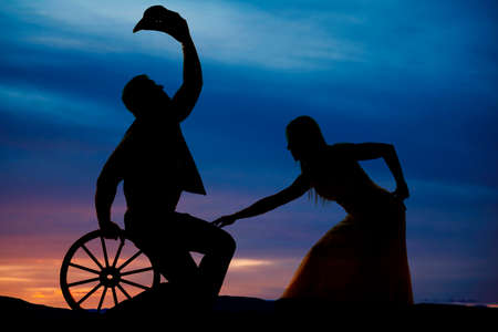 A silhouette of a woman bending down touching the leg of her cowboy.の写真素材