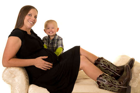 A pregant woman with a big smile and her little boy next to her belly.の写真素材