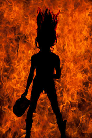 a woman in her western clothing, holding on to her hat, with a flame background.の写真素材