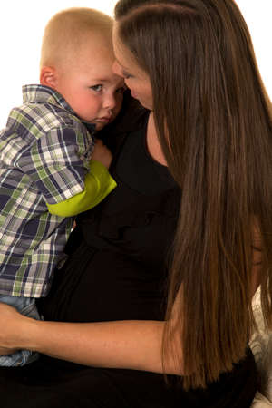 A pregnant mother holding her sad little boy.の写真素材