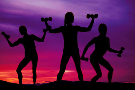 Silhouette of women working outside with weights, being fit.の写真素材