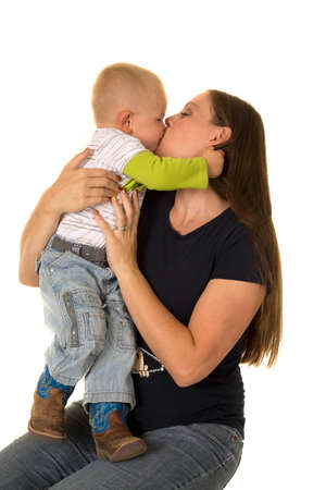 A pregnant woman with her little boy on her lap, he is giving her a big kiss.の写真素材