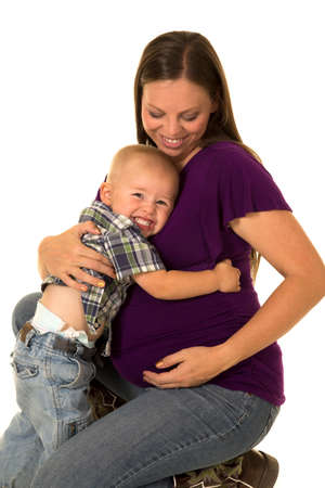 A pregnant woman with a smile, as her toddler boy gives her a big hug.の写真素材