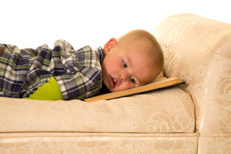a young boy laying tired of reading, resting on his book.の写真素材