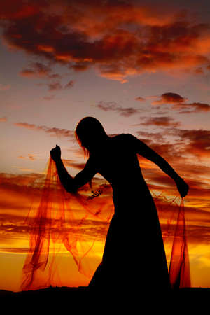 A silhouette of a woman in her wedding dress holding on to her train.の写真素材