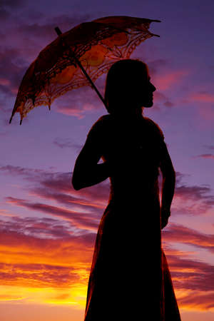 A silhouette of a woman in her dress with her umbrella.の写真素材