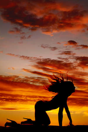 a silhouette of a woman crawling and flipping her hair back.の写真素材