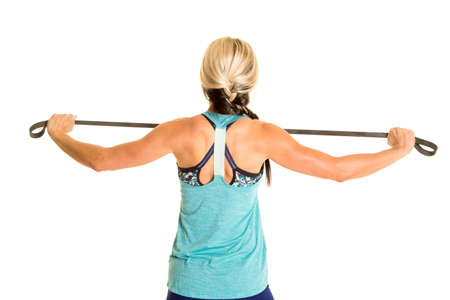 a woman pulling on a band for resistance to workout her back muscles.の写真素材