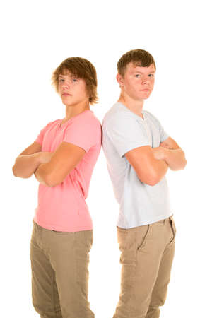 Two teenage boys with their backs together and arms folded, with serious expressions.の写真素材