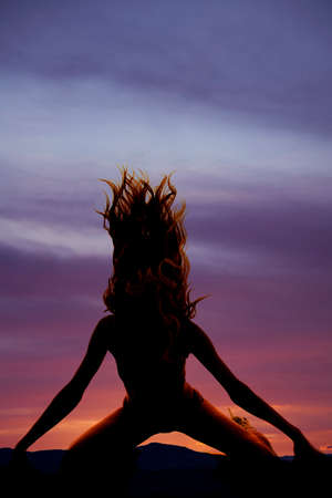 A silhouette of a woman flipping her hair kneeling.の写真素材