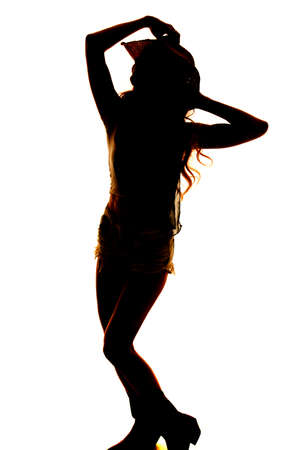 A silhouette of a cowgirl touching the top of her hat.の写真素材