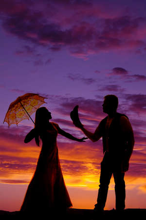 A silhouette of a cowboy taking his hat off to his lady.の写真素材