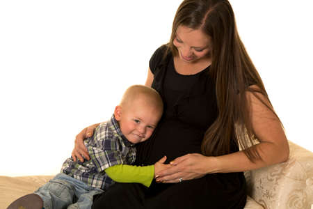 A pregnant woman with her little boys head on her belly.の写真素材