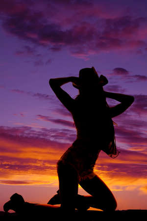 a silhouette of a woman kneeling in the outdoorsの写真素材