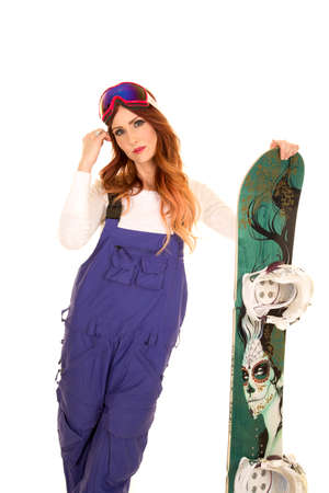 A woman standing next to her snowboard playing with her hair.の写真素材