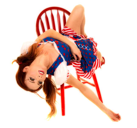 A woman with red hair in her costume laying back on her red chair.の写真素材