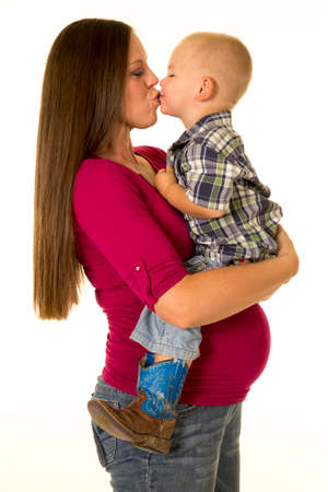 A pregnant woman giving her little toddler a big kiss.の写真素材