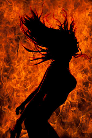A silhouette of a woman with a fire flame background, she is flipping her hair.の写真素材