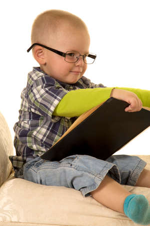 A young boy holding on to a book with glasses on his face.の写真素材