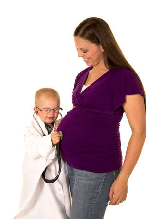 A young boy in his lab coat being a doctor, and listening to a baby with his stethoscope.の写真素材