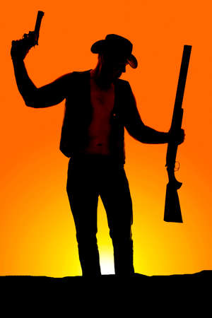 a silhouette of a cowboy with a pistol and shotgun in his hands.の写真素材