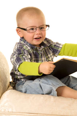 A young boy with a smile and glasses, holding on to a book.の写真素材