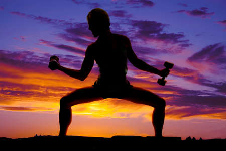 A silhouette of a woman doing a workout in the outdoors.の写真素材
