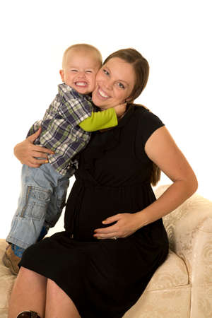 A pregnant woman with her toddler boy, he is giving her a big hug.の写真素材