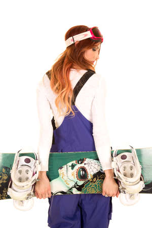 a woman standing and holding on to her snowboard looking over her shoulder.の写真素材