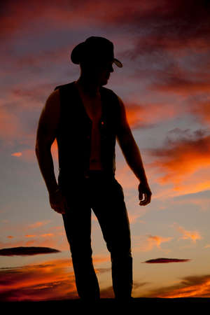 a silhouette of a cowboy in the outdoors, standing and looking down.の写真素材