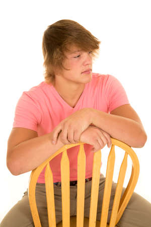A teenage boy sitting on a chair looking to the side with a serious expression on his face.の写真素材