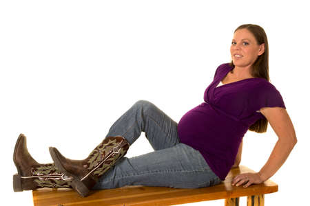 A pregnant woman with a smile with her feet up on a wooden bench.の写真素材
