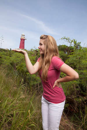 A girl with her palm up with a light house on her hand.の写真素材