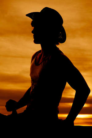 Silhouette of a teen cowboy sitting in the saddle on his horse.の写真素材