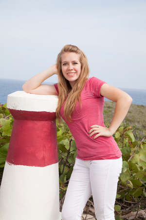 A girl leaning on a pillar with a smile on her lips.の写真素材