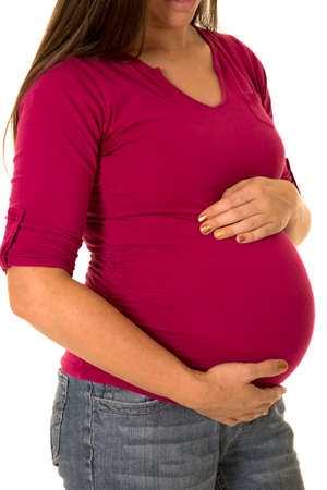 a pregnant woman with her hands on her belly looking down.の写真素材