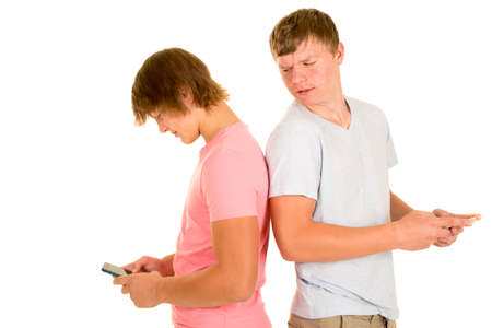 A teenage boy looking over his friends shoulder at what he is texting.の写真素材