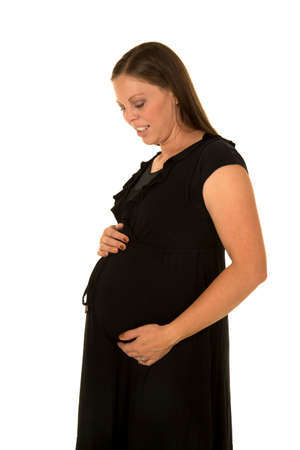 A pregnant woman looking down at her belly with a small smile.の写真素材