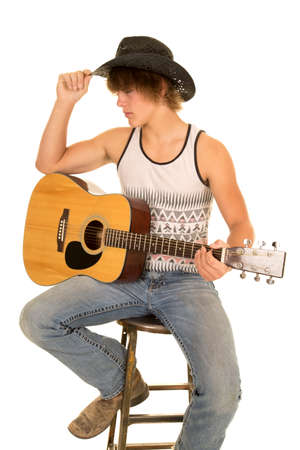 a young cowboy sitting on a stool with his guitar on his leg.の写真素材
