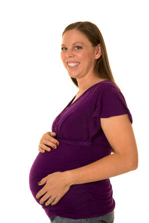 A pregnant woman with a big smile, holding on to her belly.の写真素材