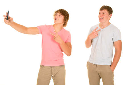 Two boys taking a picture with their cell phone.の写真素材
