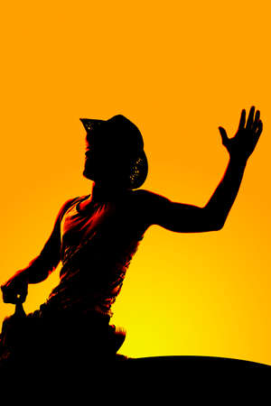 a silhouette of a cowboy riding his horse with his arm out.の写真素材