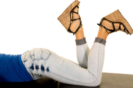 A woman laying on her stomach with her legs kicked up.の写真素材