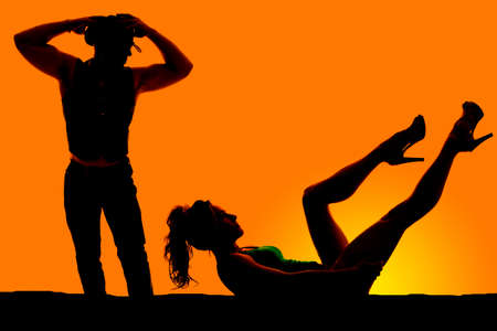 A silhouette of a cowboy looking down at his lady.の写真素材