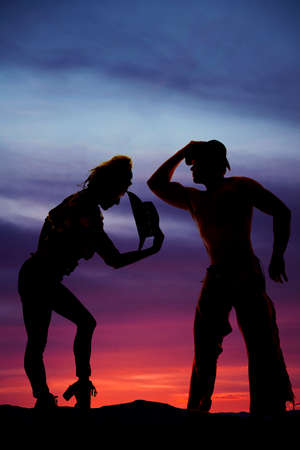 A silhouette of a cowboy standing next to his cowgirlの写真素材