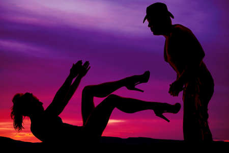 A silhouette of a woman reaching up towards her cowboy.の写真素材