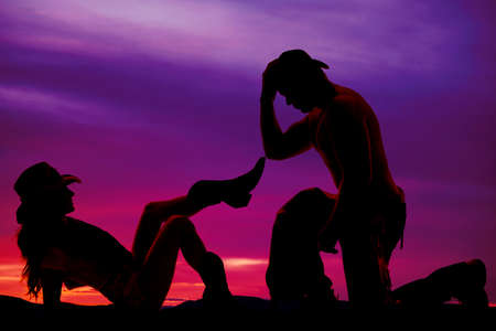 A cowgirl laying back while her cowboy is kneeling in front of her.の写真素材